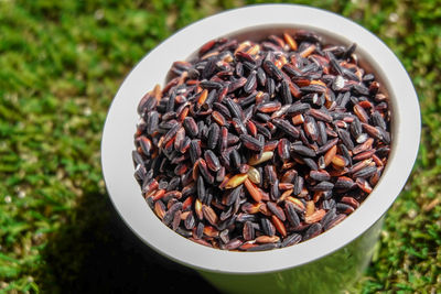 Red rice in a bowl on green background.