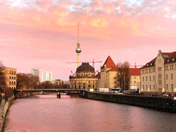 Buildings at waterfront against cloudy sky