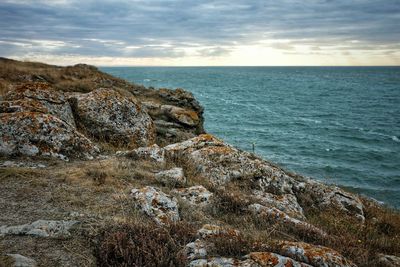 Scenic view of rocks by sea against sky