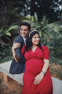 Thoughtful pregnant woman sitting with boyfriend on seat at park