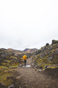 Rear view of man walking on road against sky