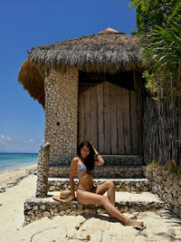 Portrait of woman in bikini sitting at beach