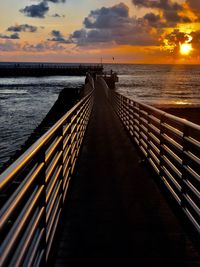 Pier over sea against sky during sunset