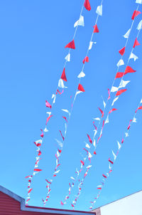 Low angle view of multi colored umbrellas against blue sky