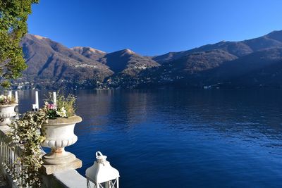 Scenic view of lake and mountains against clear blue sky