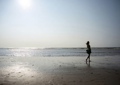 Silhouette woman walking at beach against sky