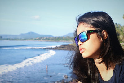 Portrait of beautiful woman at beach against sky