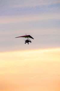 Low angle view of airplane flying against sky during sunset