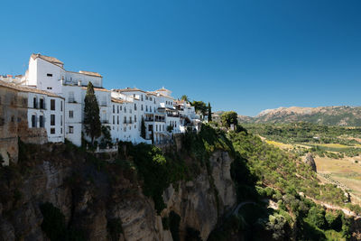 Panoramic view of buildings and mountains against clear blue sky