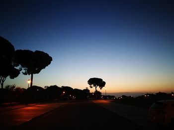 Silhouette trees against clear sky at sunset