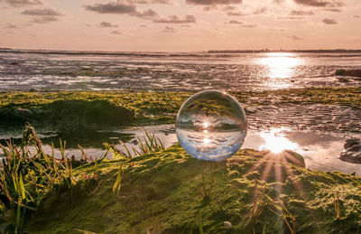 Water on beach against sky during sunset