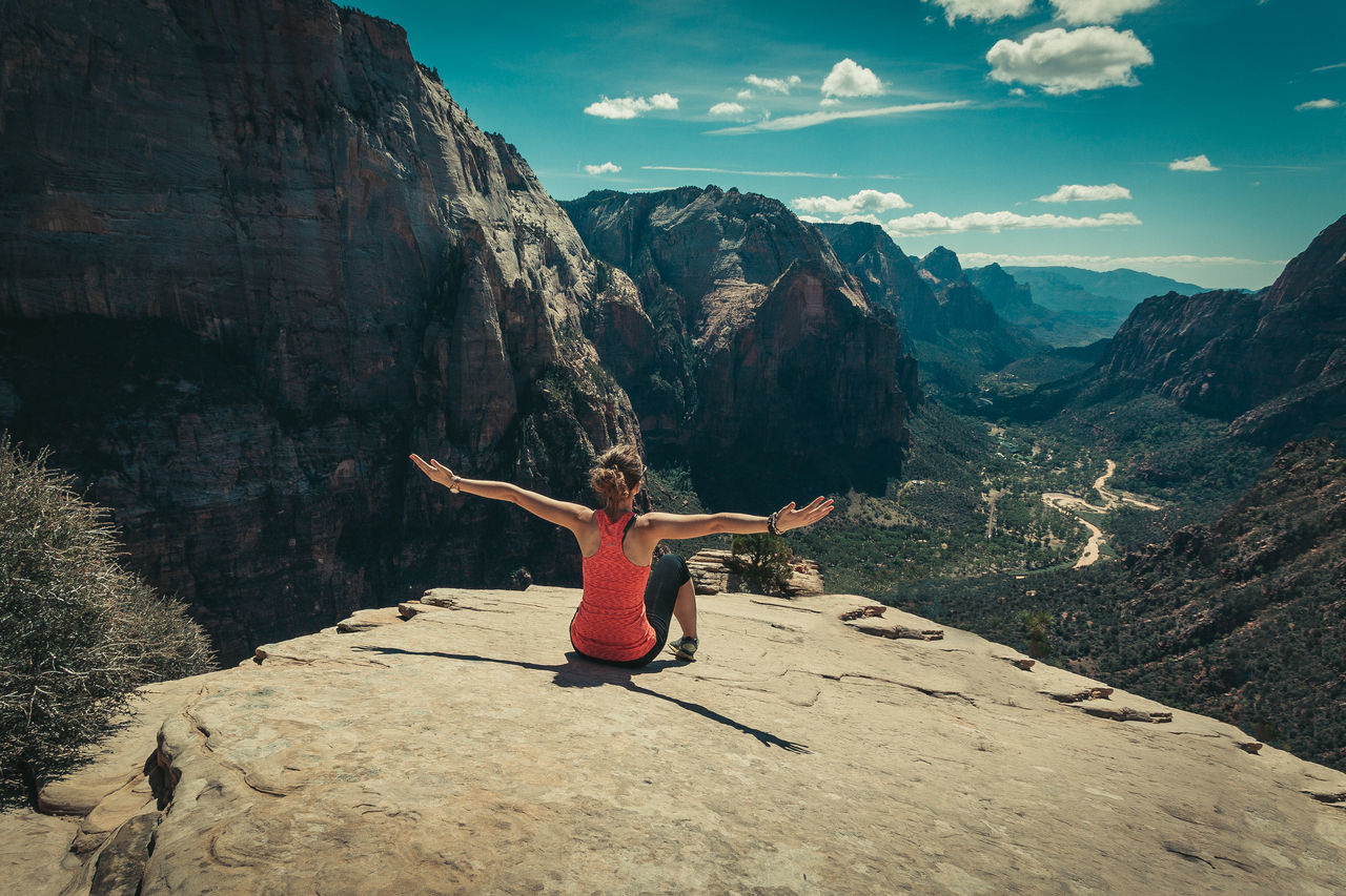 WOMAN ON ROCK AGAINST SKY