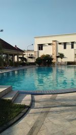 Swimming pool by buildings against clear blue sky