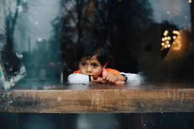 Thoughtful boy looking through window