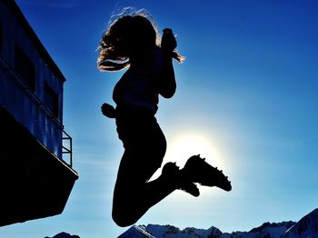 Low angle view of silhouette man jumping against sky