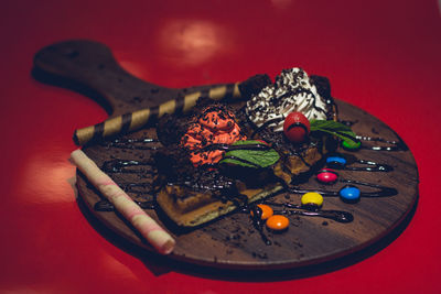 Close-up of hand holding ice cream over red background