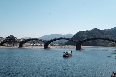 Bridge over river in city against clear sky