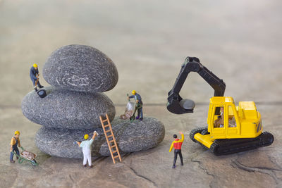 Figurines working on stones by crane at construction site
