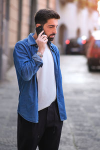 Young man using mobile phone while standing on street