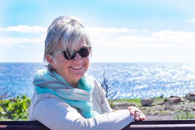 Portrait of smiling young woman in sea against sky