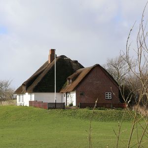 Barn on field by houses against sky