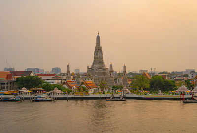 View of temple building by river against sky