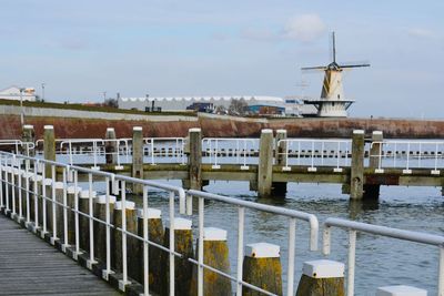 Wooden post by river against sky