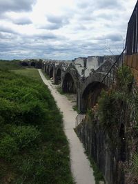 Arch bridge amidst plants and buildings against sky