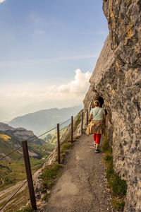 Rear view of woman walking on mountain against sky