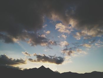 Low angle view of silhouette mountains against dramatic sky