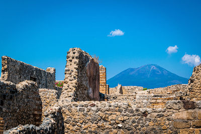 Low angle view of castle on mountain against blue sky