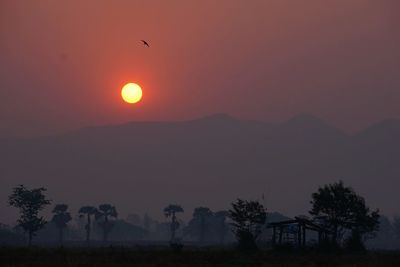 Scenic view of silhouette mountains against orange sky