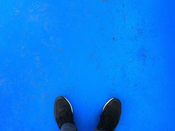 Low section of man standing against blue wall