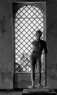 Statue of man standing by window