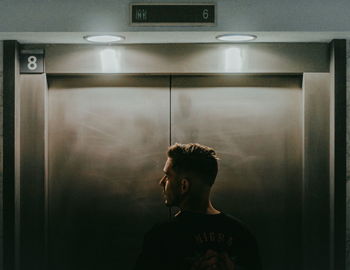 Young man standing in illuminated room