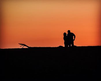 Silhouette men on fire against sky during sunset