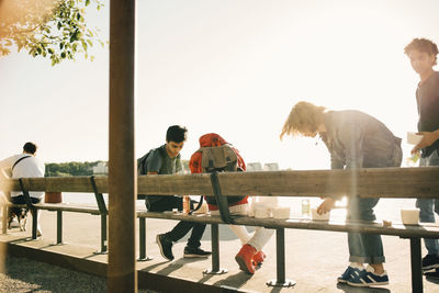 People sitting on railing against clear sky