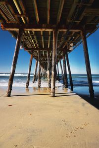 Silhouette pier on beach against sky