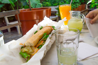 Close-up of fresh lemonade and sandwich served on table at back yard
