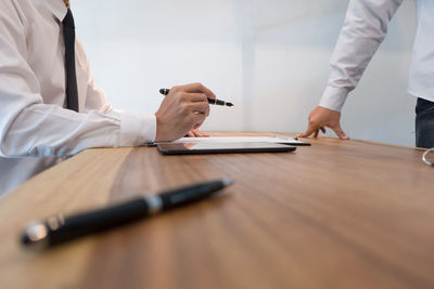 Midsection of man holding umbrella on table