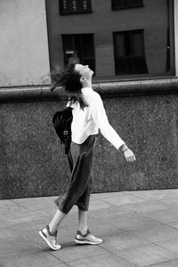 Side view of woman standing on footpath against building