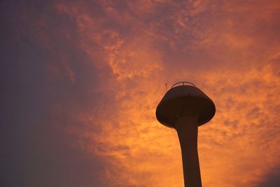 Low angle view of water tower against orange sky