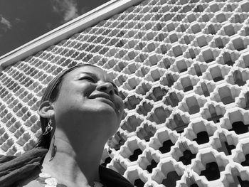 Low angle view of mid adult woman standing by patterned wall