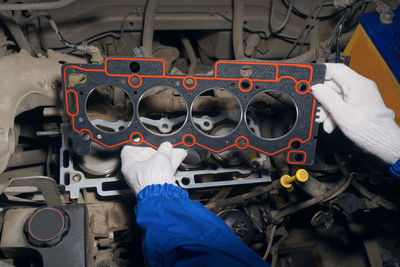 An auto mechanic installs a gasket on a car engine block.