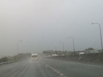 Cars on road against sky during rainy season