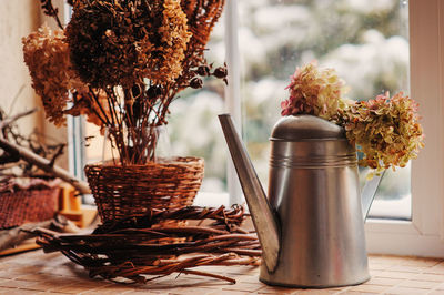 Close-up of teapot and flowers in vase on table