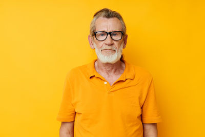 Portrait of young man standing against yellow background