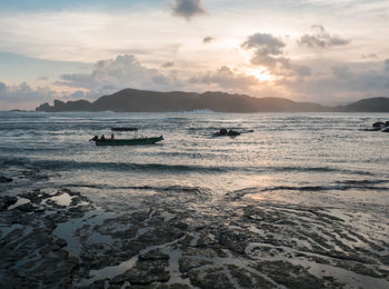 Scenic view of beach against cloudy sky during sunset