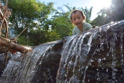 Portrait of happy boy standing on rock against trees