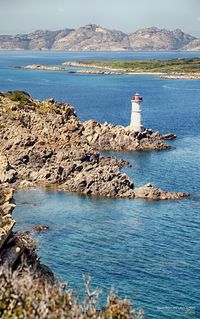 Lighthouse by sea on sunny day